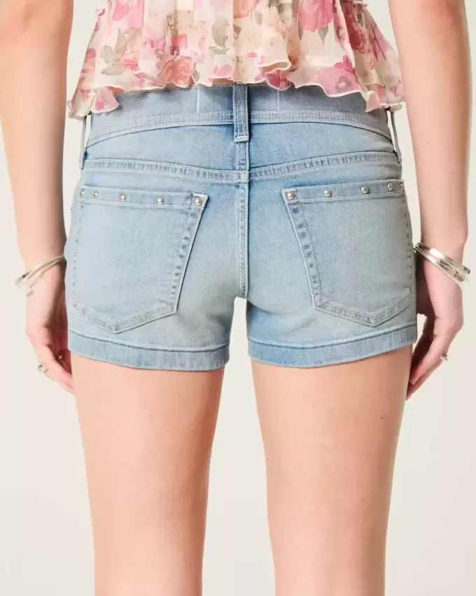 Low-Rise-Shortie-Shorts aus Denim mit mittlerer Waschung und Nieten Low-Rise-Shortie-Shorts aus Denim mit mittlerer Waschung und Nieten